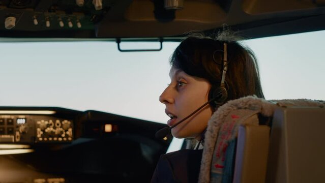 Female copilot pushing dashboard buttons to start engine and fly airplane, using aviation command on control panel board to takeoff. Cockpit navigation with windscreen and radar compass. Close up.