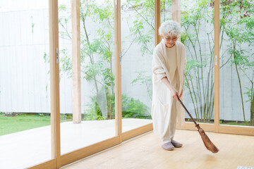 ほうきで床を掃除するミドル女性