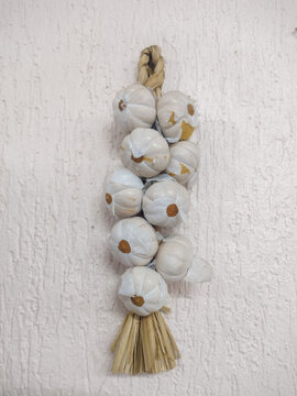 White garlic branch in wall mounted set closeup photo. Seasoning image as a wall decoration or to scare away evil eye, spells or vampires.