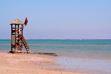 Rescue post on the sea coast. Rescue tower on the beach. Red flag on the rescue tower