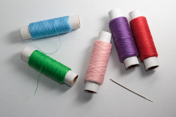 Green, grey, pink and purple threads on the white background