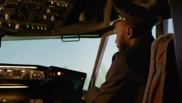 Portrait of male copilot pressing power switch buttons to takeoff and fly airplane, using control panel command in cockpit. Aircraft and navigation with radar compass on dashboard. Handheld shot.