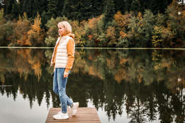 Fototapeta na wymiar The woman is in the autumn park. Autumn atmosphere, scenic view of the river