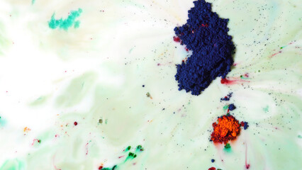 Colorful background with milky substance and bright dry blue inks floating on it. Top view of colored dry powder paints on the surface of white liquid.