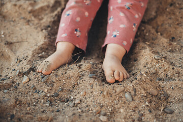 In the morning, a little girl playing with stones and sand, dressed in pink. Positive emotions.