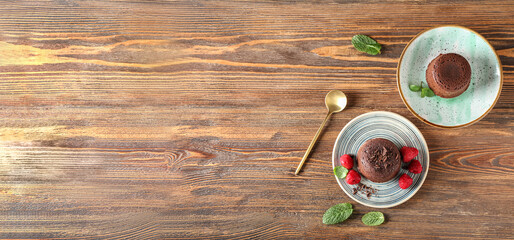 Plates with tasty lava cake and raspberry on wooden background with space for text
