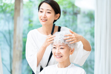 美容院でカットする女性と日本人女性