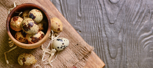 Bowl of fresh quail eggs on wooden background with space for text