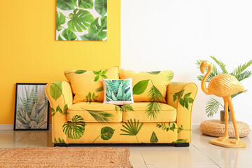 Comfortable yellow sofa with print of tropical leaves in living room