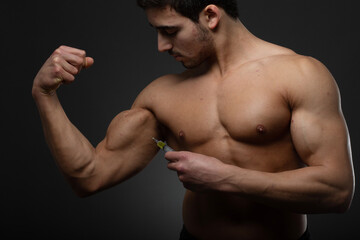 Muscular man with a syringe in his hand. User of anabolic steroids for strength training.