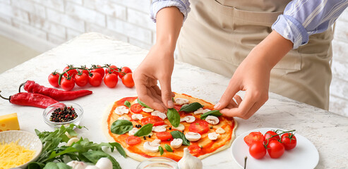 Obraz na płótnie Canvas Woman cooking tasty pizza in kitchen, closeup