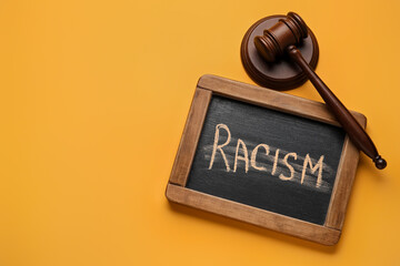 Chalkboard with written word RACISM and judge gavel on color background
