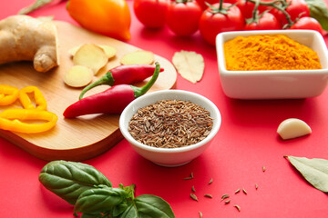 Bowls with spices and vegetables on red background