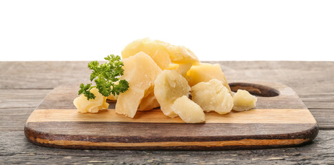 Wooden board with pieces of tasty Parmesan cheese on table against white background