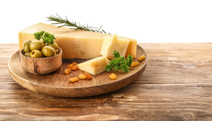 Plate with pieces of tasty Parmesan cheese and green olives on table against white background