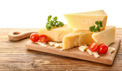Wooden board with pieces of tasty Parmesan cheese on table against white background