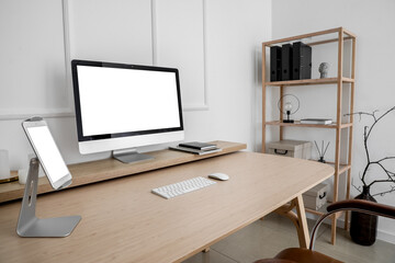 Fototapeta na wymiar Modern workplace with computer and tablet near light wall