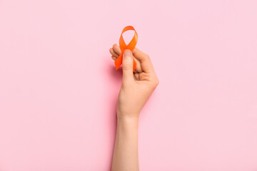 Woman with orange awareness ribbon on pink background. Kidney cancer concept