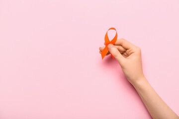Woman with orange awareness ribbon on pink background. Kidney cancer concept