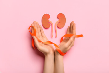 Woman with orange awareness ribbon and paper kidneys on pink background
