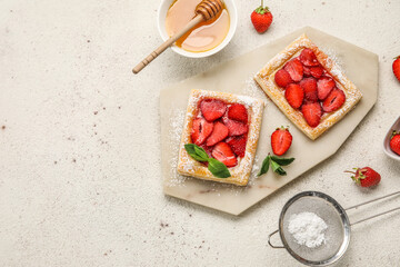 Board with sugar powdered puff pastry, strawberry and honey on light background