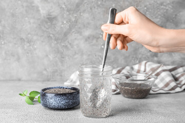 Woman stirring chia seeds in glass of water, closeup