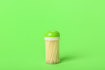 Holder with toothpicks on green background