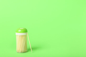 Holder with wooden toothpicks on green background