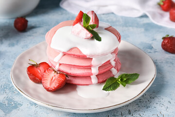 Plate of tasty pink pancakes with strawberry and sauce on color background