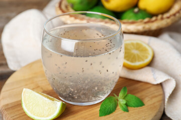 Glass of drink with chia seeds, slice of lime and mint leaves on wooden board