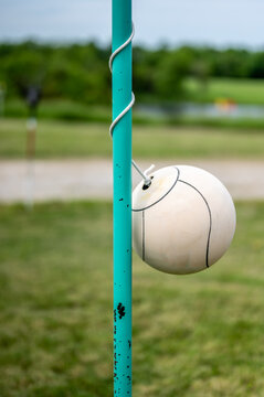 Tetherball sitting idle next to the pole in a backyard.