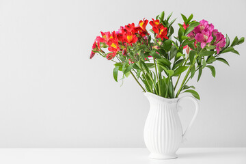 Vase with alstroemeria flowers flowers on light background