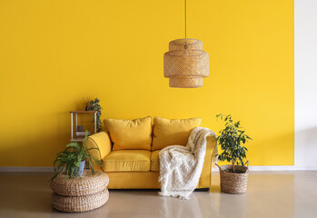 Comfortable couch, shelving unit and houseplants near yellow wall