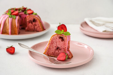 Plate with piece of delicious strawberry cake on light background