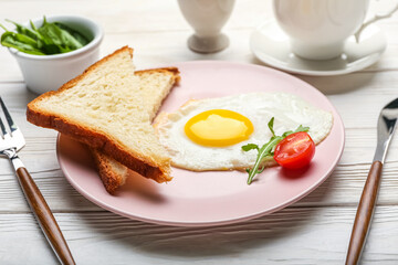 Fototapeta na wymiar Plate with tasty fried egg and pieces of fresh bread on light wooden background, closeup