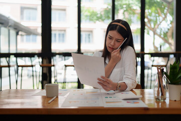Image of Young woman with a cell phone working with paperwork. studying or working from home online concept.
