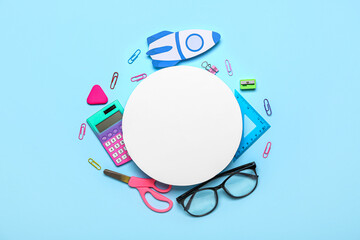 Blank paper sheet with rocket, school stationery and eyeglasses on blue background