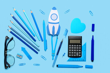 Paper rocket with school stationery and eyeglasses on blue background