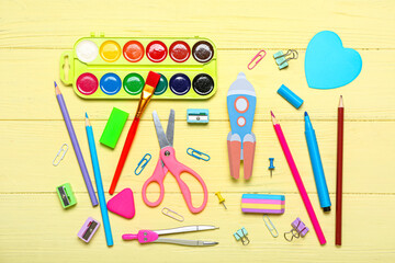 Paper rocket with school stationery on yellow wooden background