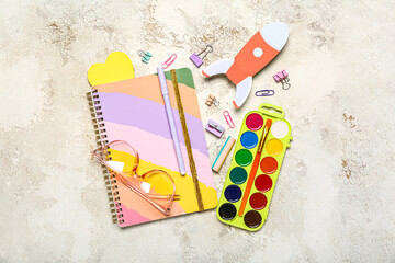Paper rocket with school stationery and eyeglasses on grunge background