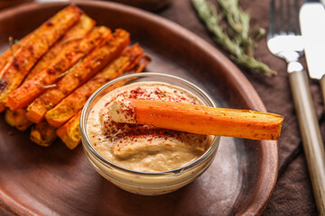 Bowl of tasty sauce with baked carrots, closeup