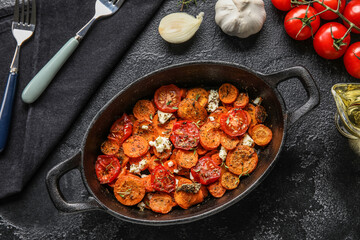 Frying pan with baked vegetables on dark background