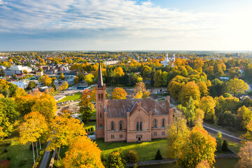 Beautiful aerial view of Evangelical Reformed Church in Birzai surrounded by autumn vegetation on sunny fall day.