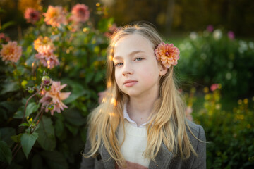 Beautiful preteen girl in blossoming dahlia field. Child picking fresh flowers in dahlia meadow on autumn day.