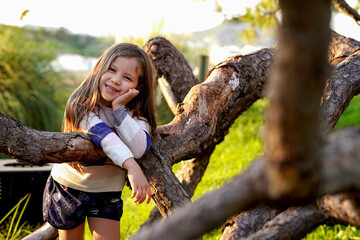 Niña feliz alegre sonriente disfrutando de un hermoso dia al aire libre al exterior en el tronco...