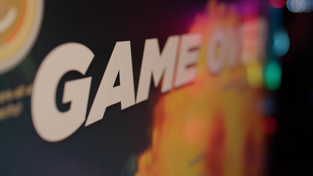 Extreme closeup on game over text on computer screen after failing level in online space shooter on gaming pc setup. Losing message and statistics on monitor at the end of multiplayer session.