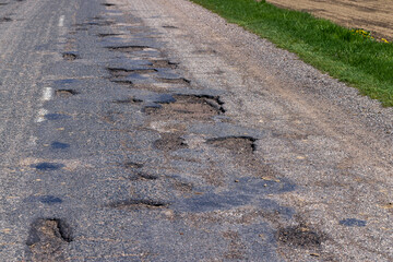 poor paved road with a lot of holes and potholes