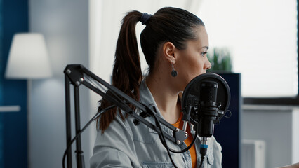 Social media influencer hosting radio talk show while talking to internet audience. Young woman...