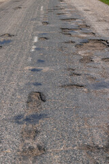poor paved road with a lot of holes and potholes