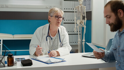 Obraz premium Medic signing prescription paper to give medicine and support to sick patient at checkup visit. Doctor helping young adult with drugs treatment and medication at health care examination.